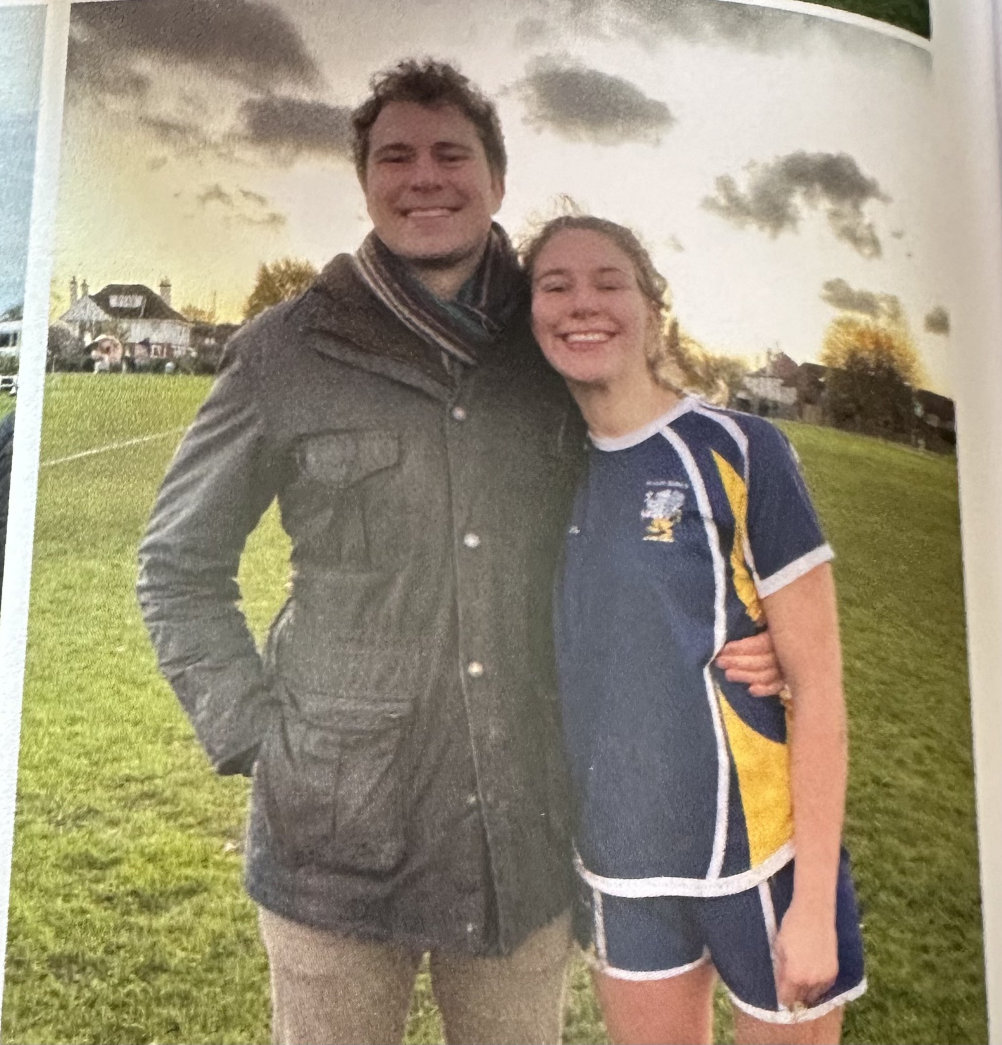 Eliza smiling with a friend on a rugby pitch.